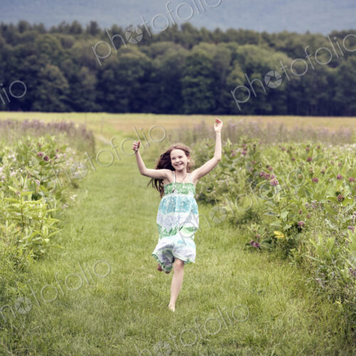 A girl running through a meadowwith her arms above her head. A girl running through a meadowwith her arms above her head.
