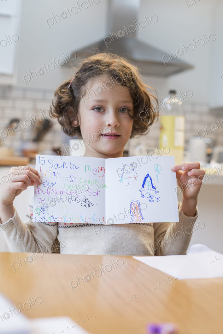 A girl showing her home made Christmas card, a letter to Santa Claus, with drawings…