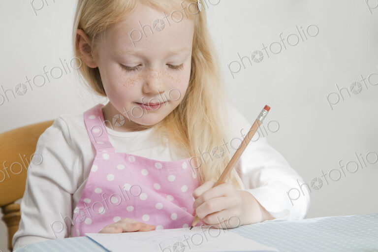 A girl sitting at a table drawing.