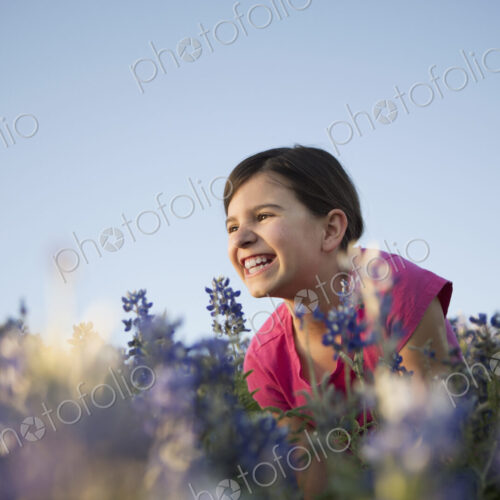 A girl sitting in a field of tall grass and blue wild flowers. A girl sitting in a field of tall grass and blue wild flowers.