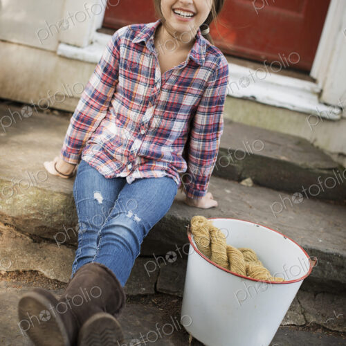 A girl sitting on a step, with a large iron pail and gloves. A girl sitting on a step, with a large iron pail and gloves.