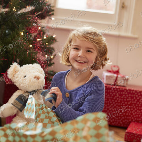 A girl unwrapping a soft toy, a teddy bear, on Christmas Day. A girl unwrapping a soft toy, a teddy bear, on Christmas Day.