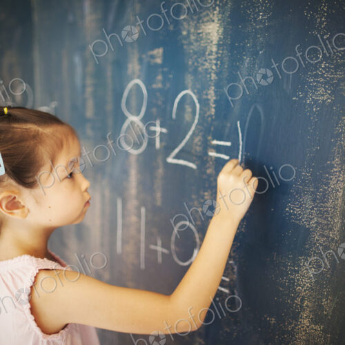 A girl writing in chalk on a chalkboard in school. A girl writing in chalk on a chalkboard in school.