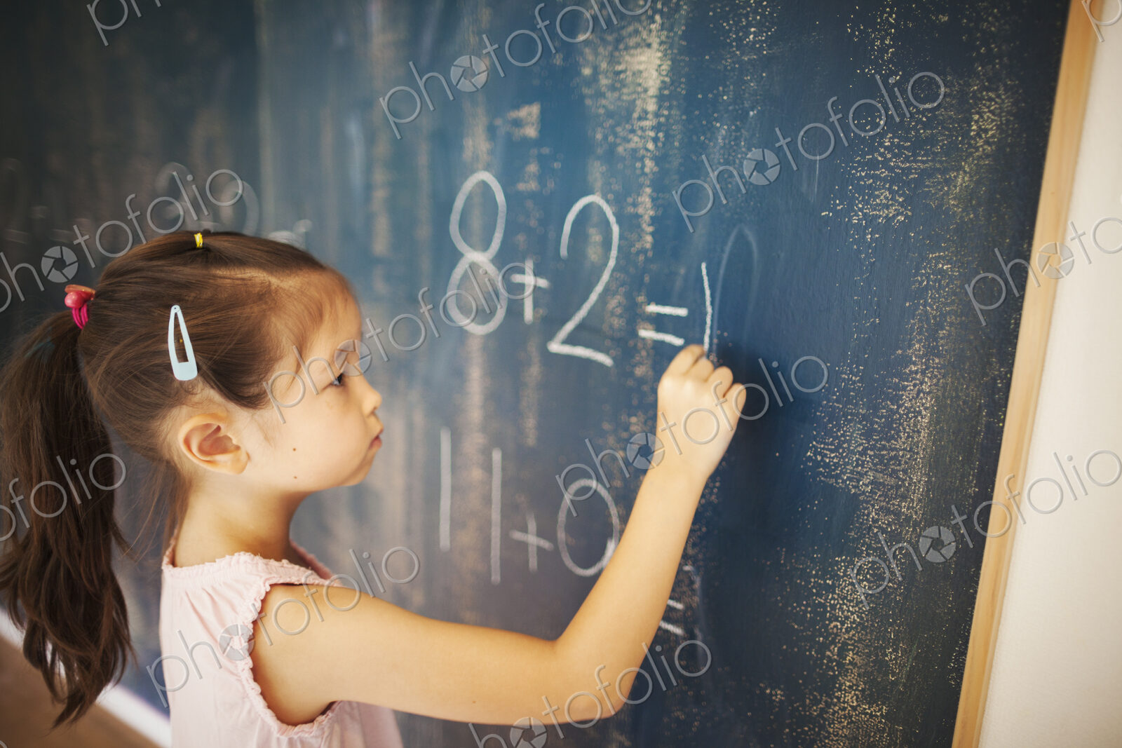 A girl writing in chalk on a chalkboard in school.