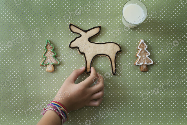 A girl's hand arranging an organic homemade Christmas cookies in the shape of a…