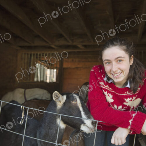 A goat farm. A young girl leaning on the barrier of the goat shed, with a group of… A goat farm. A young girl leaning on the barrier of the goat shed, with a group of…