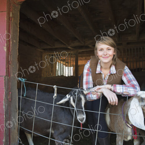 A goat farm. A young girl leaning on the barrier of the goat shed, with two animals… A goat farm. A young girl leaning on the barrier of the goat shed, with two animals…