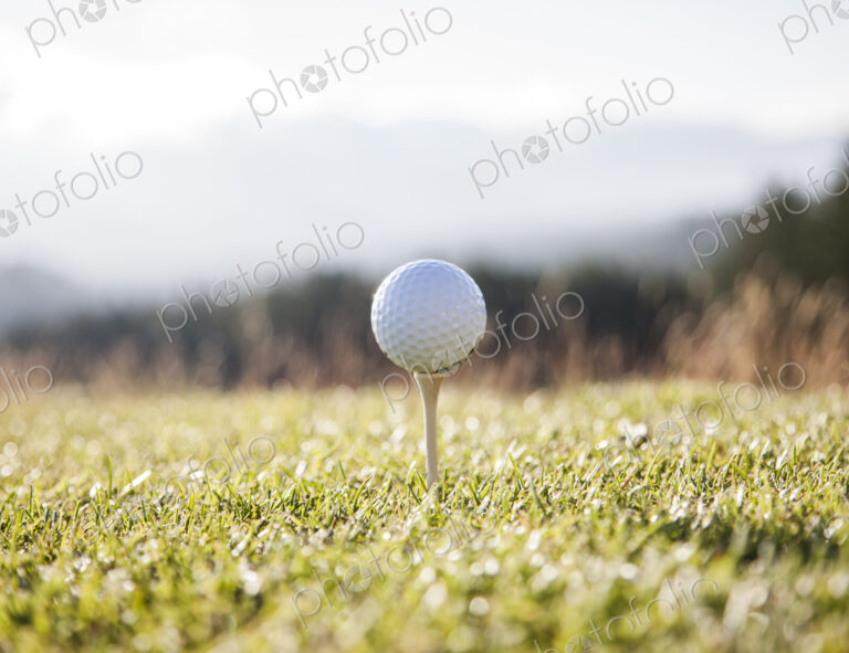 A golf ball on a tee ready to be hit.