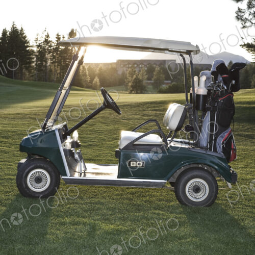 A golf cart with bags sitting on a golf course. A golf cart with bags sitting on a golf course.