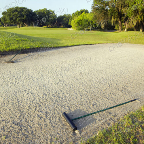A golf course bunker, sand trap with a rake A golf course bunker, sand trap with a rake
