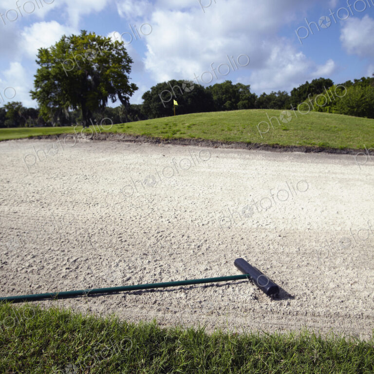 A golf course bunker, sand trap with a rake