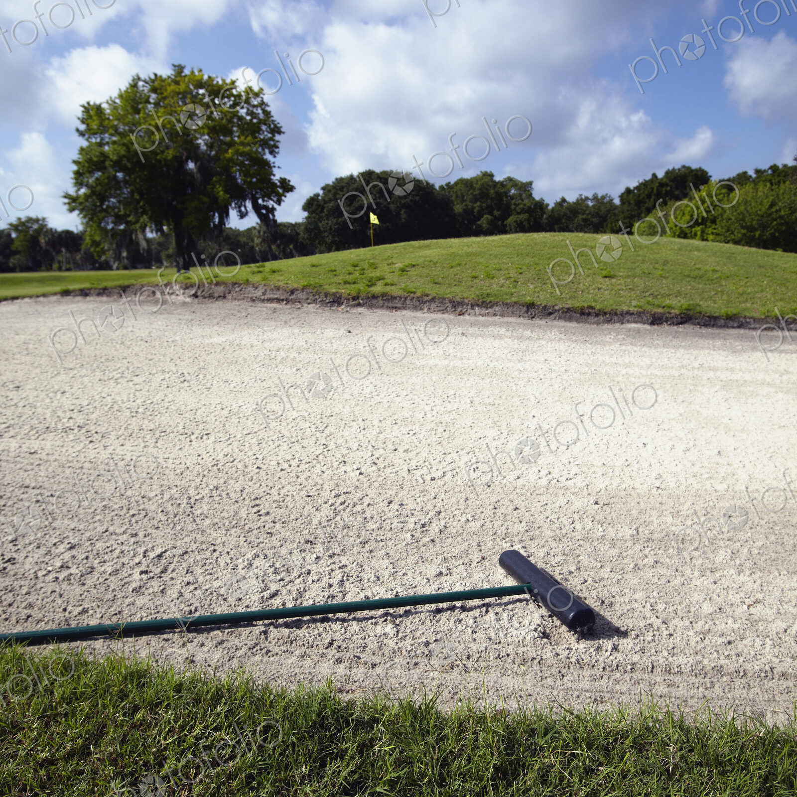 A golf course bunker, sand trap with a rake