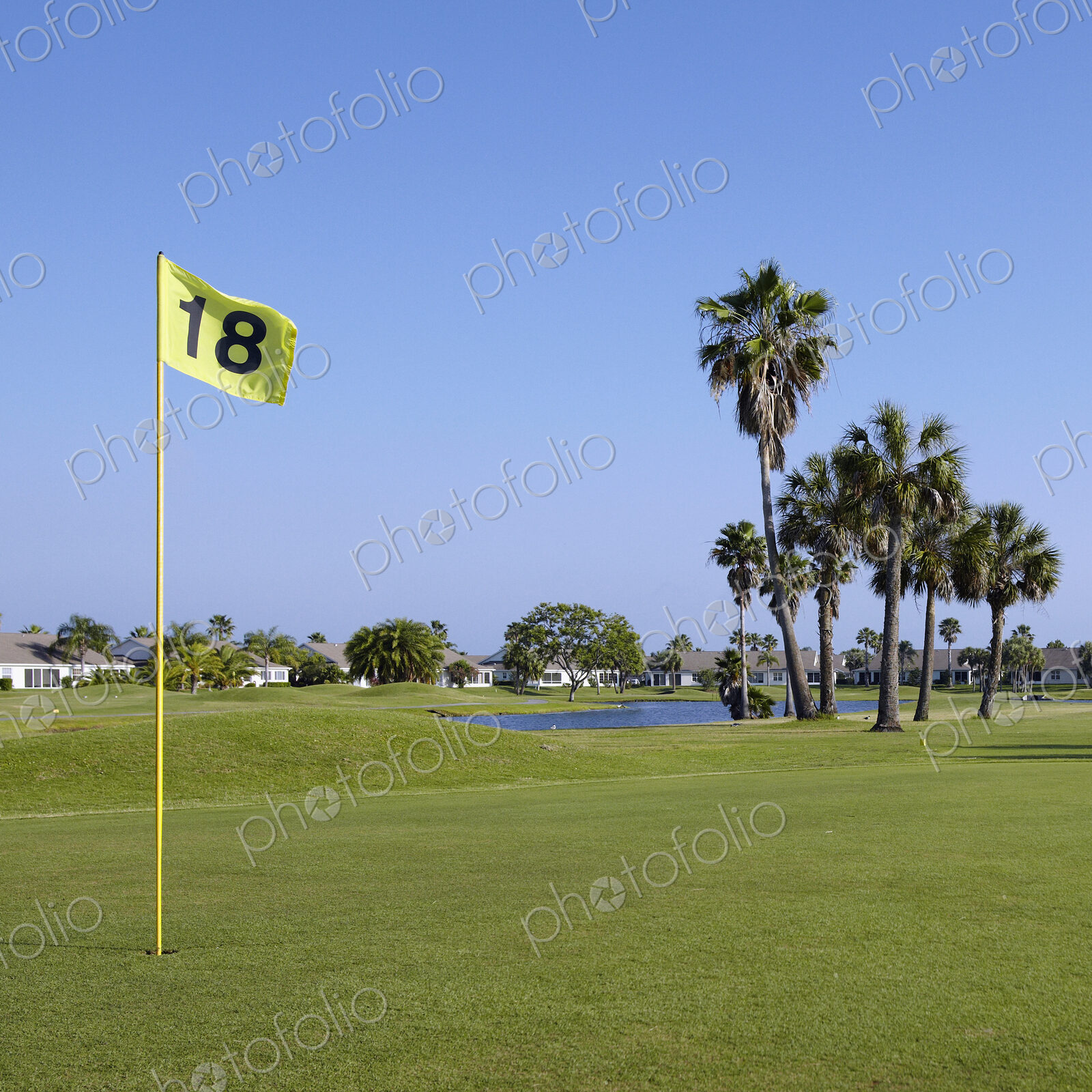 A golf course green with a yellow flag on a post in the hole.