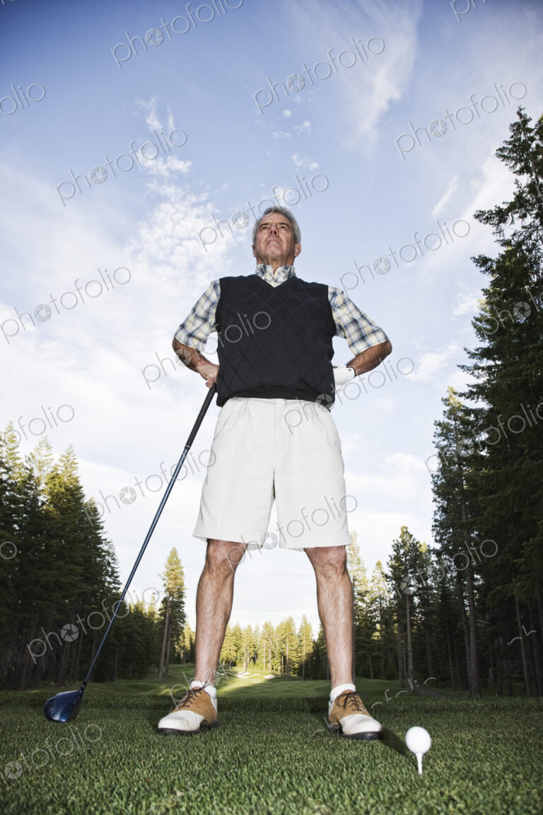 A golfer leaning on his golf club at the tee.