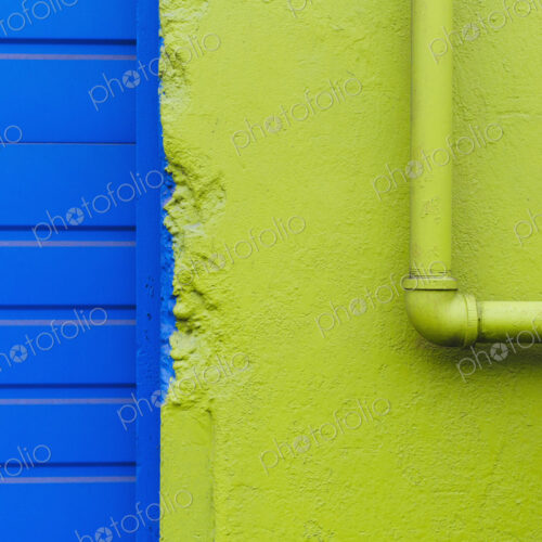 A green painted wall and pipe by a blue doorway. A green painted wall and pipe by a blue doorway.