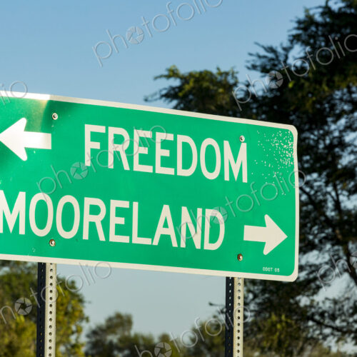 A green road signpost with an arrow pointed to Freedom, and one to Mooreland.. A green road signpost with an arrow pointed to Freedom, and one to Mooreland..