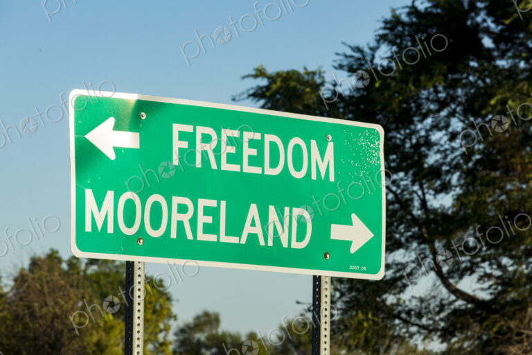 A green road signpost with an arrow pointed to Freedom, and one to Mooreland..