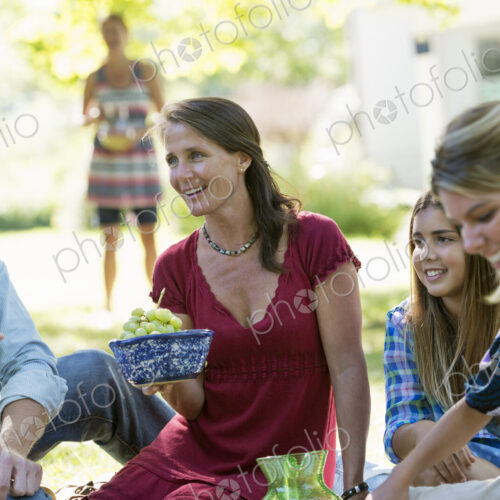 A group of adults and children sitting on the grass under the shade of a tree. A… A group of adults and children sitting on the grass under the shade of a tree. A…