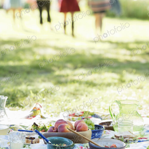 A group of adults and children sitting on the grass under the shade of a tree. A…