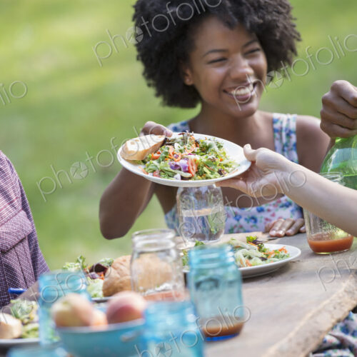 A group of adults and young people at a meal in the garden of a farmhouse.