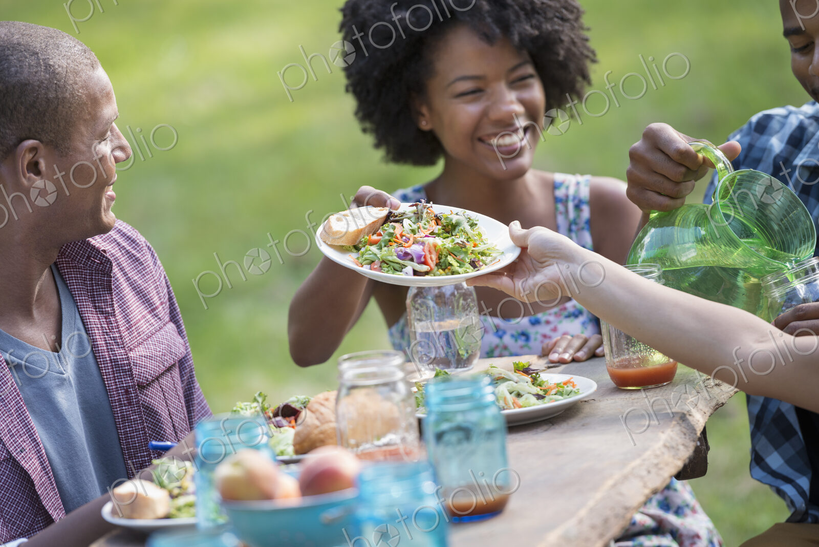 A group of adults and young people at a meal in the garden of a farmhouse.