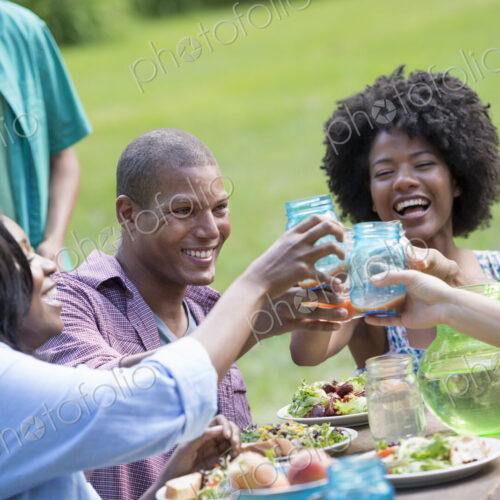 A group of adults and young people at a meal in the garden of a farmhouse.