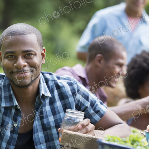 A group of adults and young people at a meal in the garden of a farmhouse.