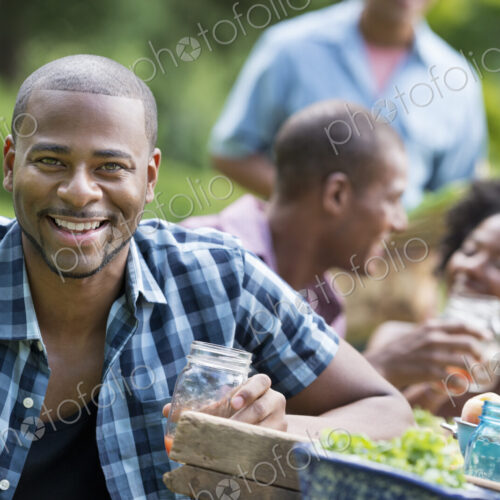 A group of adults and young people at a meal in the garden of a farmhouse.