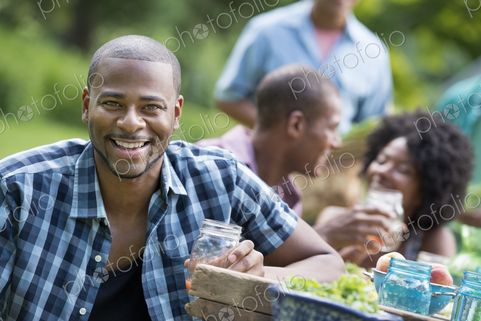 A group of adults and young people at a meal in the garden of a farmhouse.