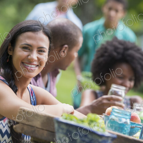 A group of adults and young people at a meal in the garden of a farmhouse.