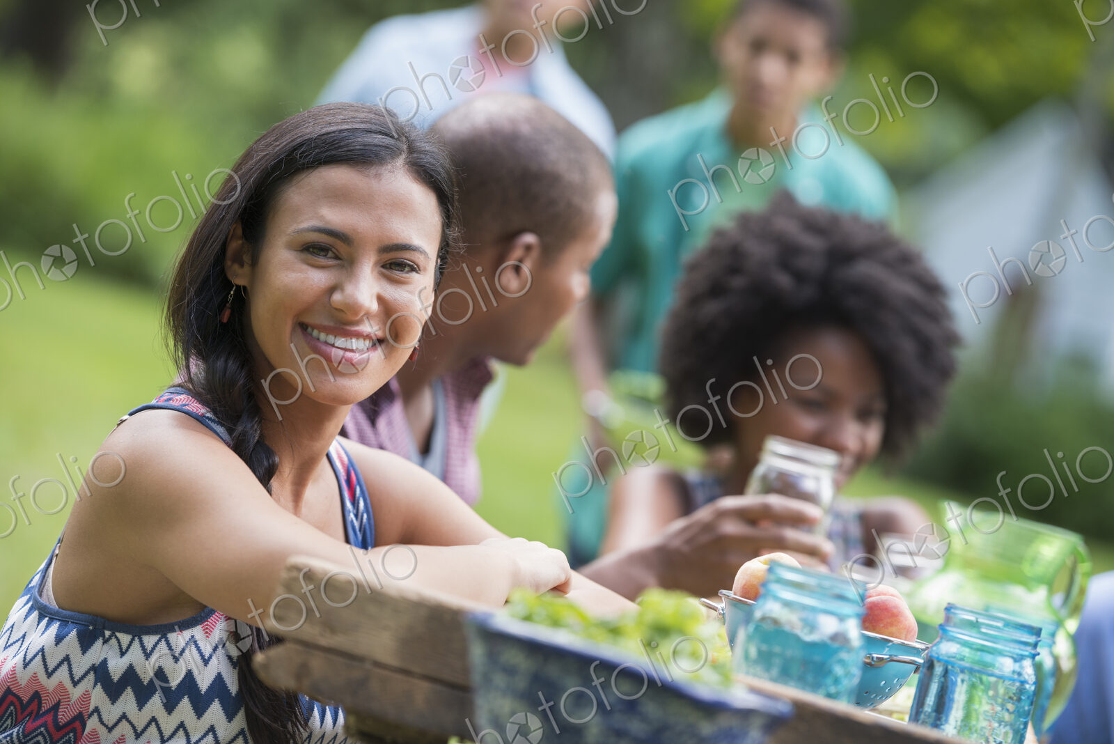 A group of adults and young people at a meal in the garden of a farmhouse.