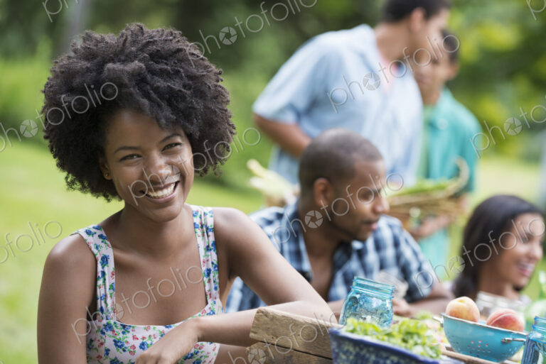 A group of adults and young people at a meal in the garden of a farmhouse.