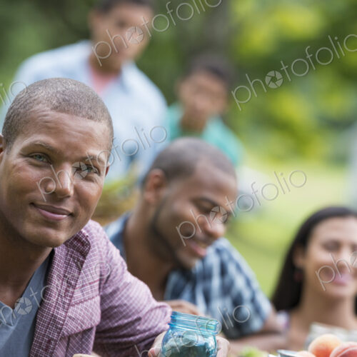 A group of adults and young people at a meal in the garden of a farmhouse. A group of adults and young people at a meal in the garden of a farmhouse.