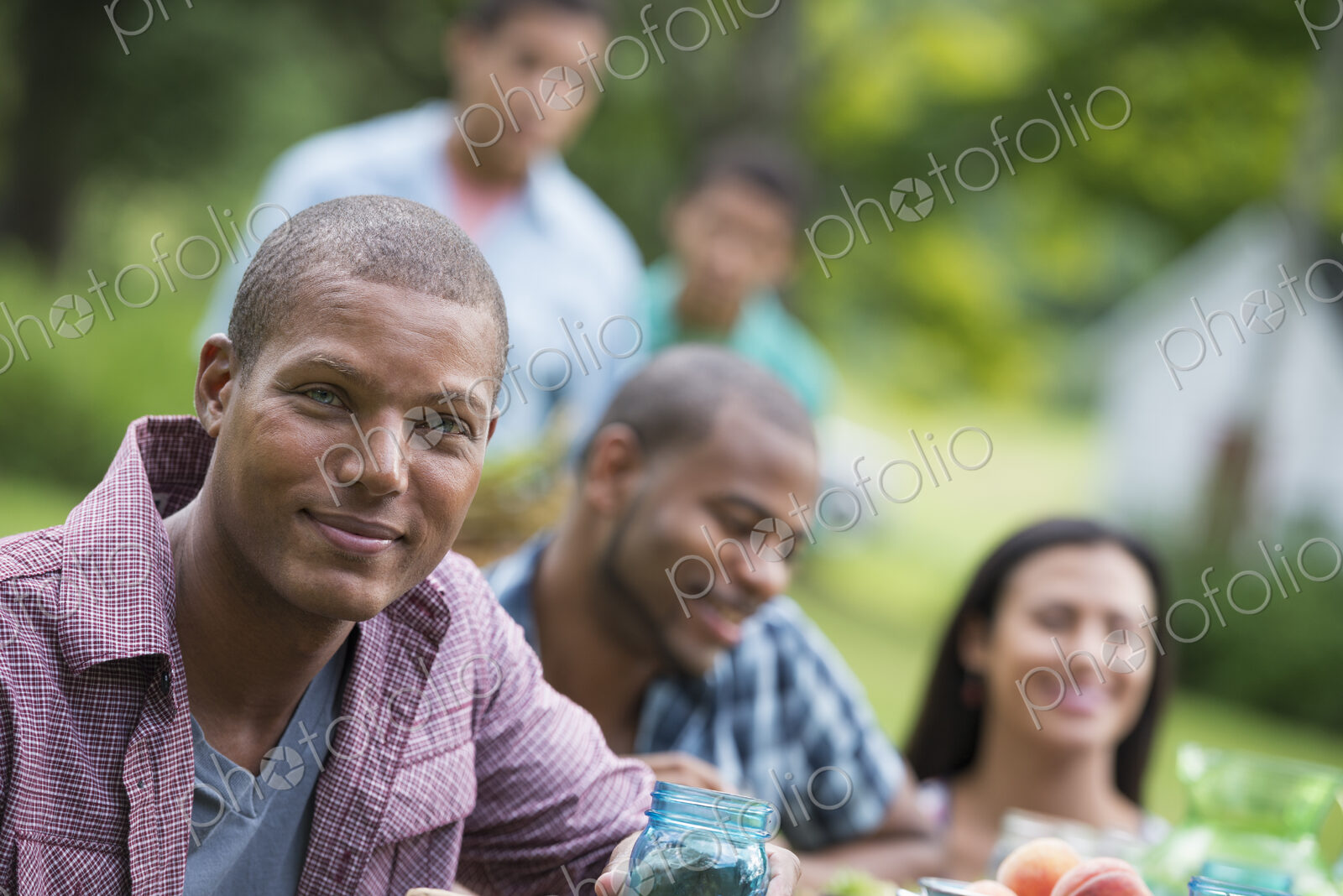 A group of adults and young people at a meal in the garden of a farmhouse.