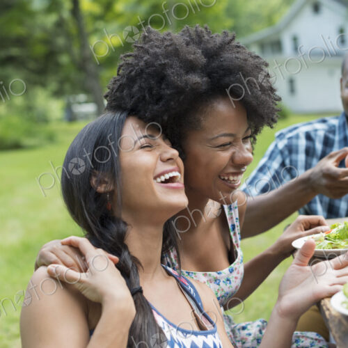 A group of adults and young people at a meal in the garden of a farmhouse. Passing…