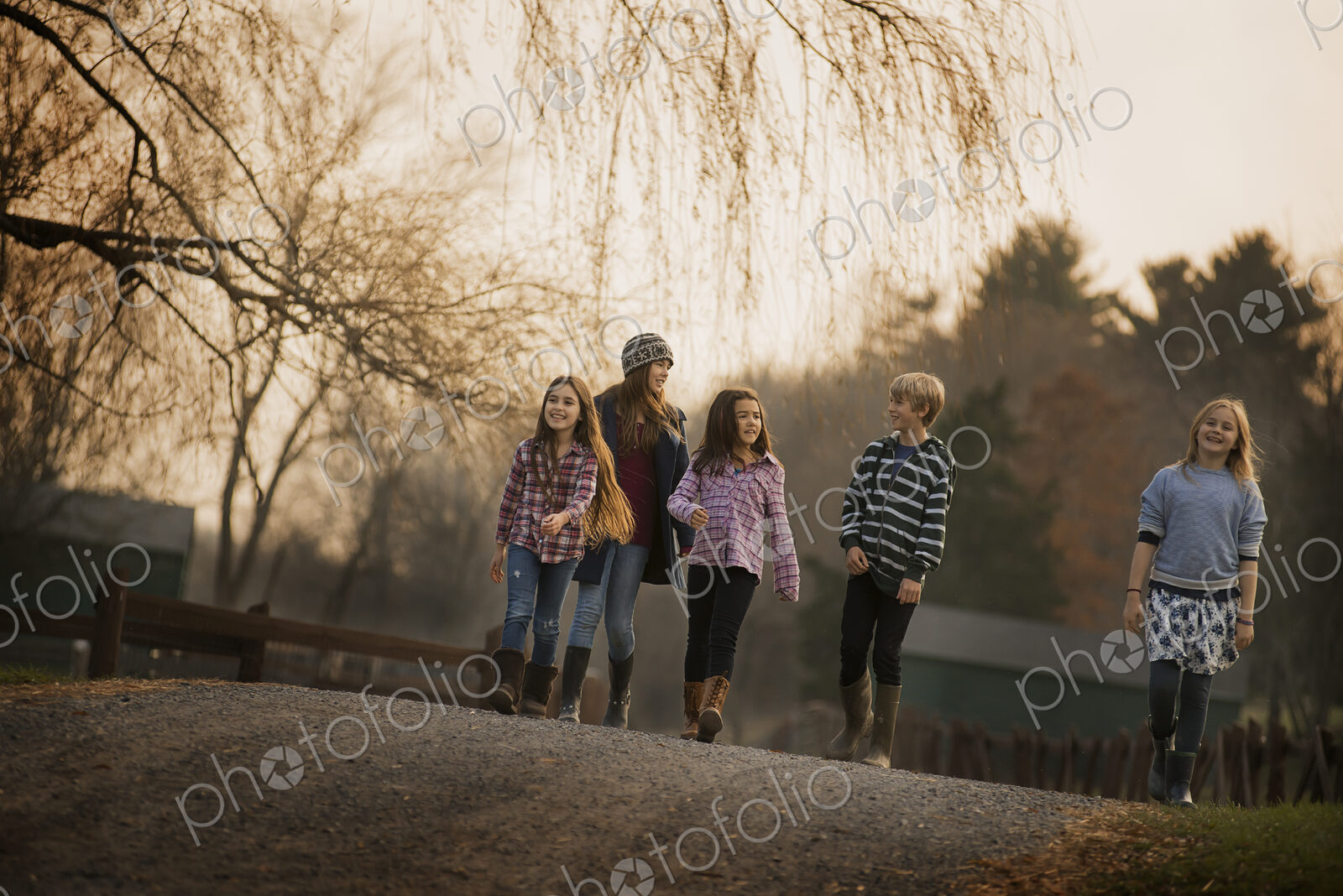 A group of children, a boy and four girls, walking along a path, on a winter’s day. An…