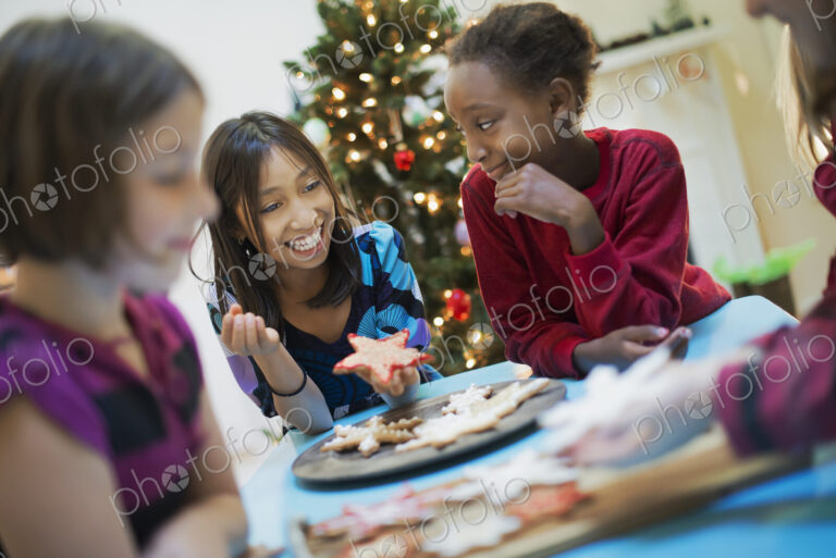 A group of children around a table, decorating organic Christmas cookies.