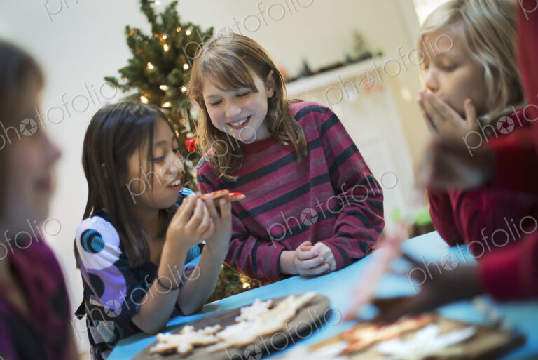 A group of children around a table, decorating organic Christmas cookies.