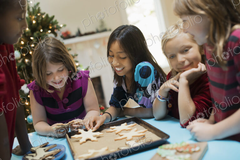 A group of children around a table, decorating organic Christmas cookies.