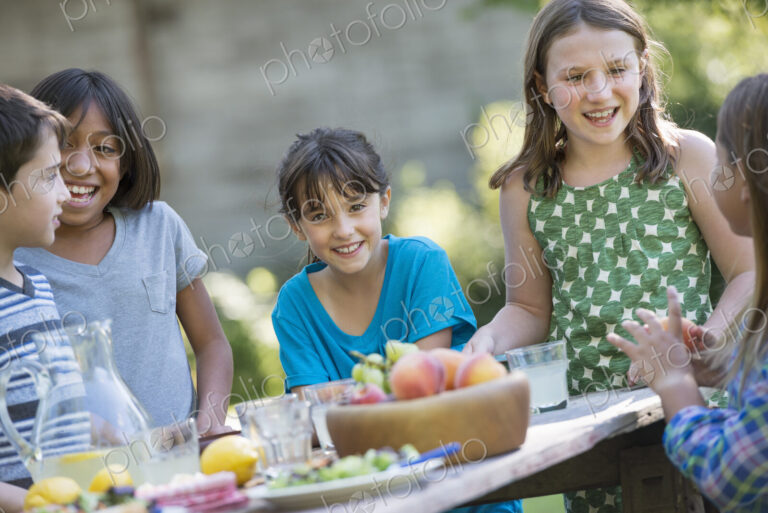 A group of children around a table, eating fresh fruitss and salads.