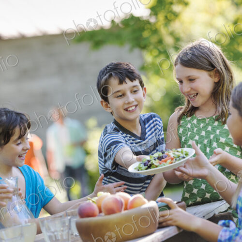 A group of children around a table, eating fresh fruitss and salads. A group of children around a table, eating fresh fruitss and salads.