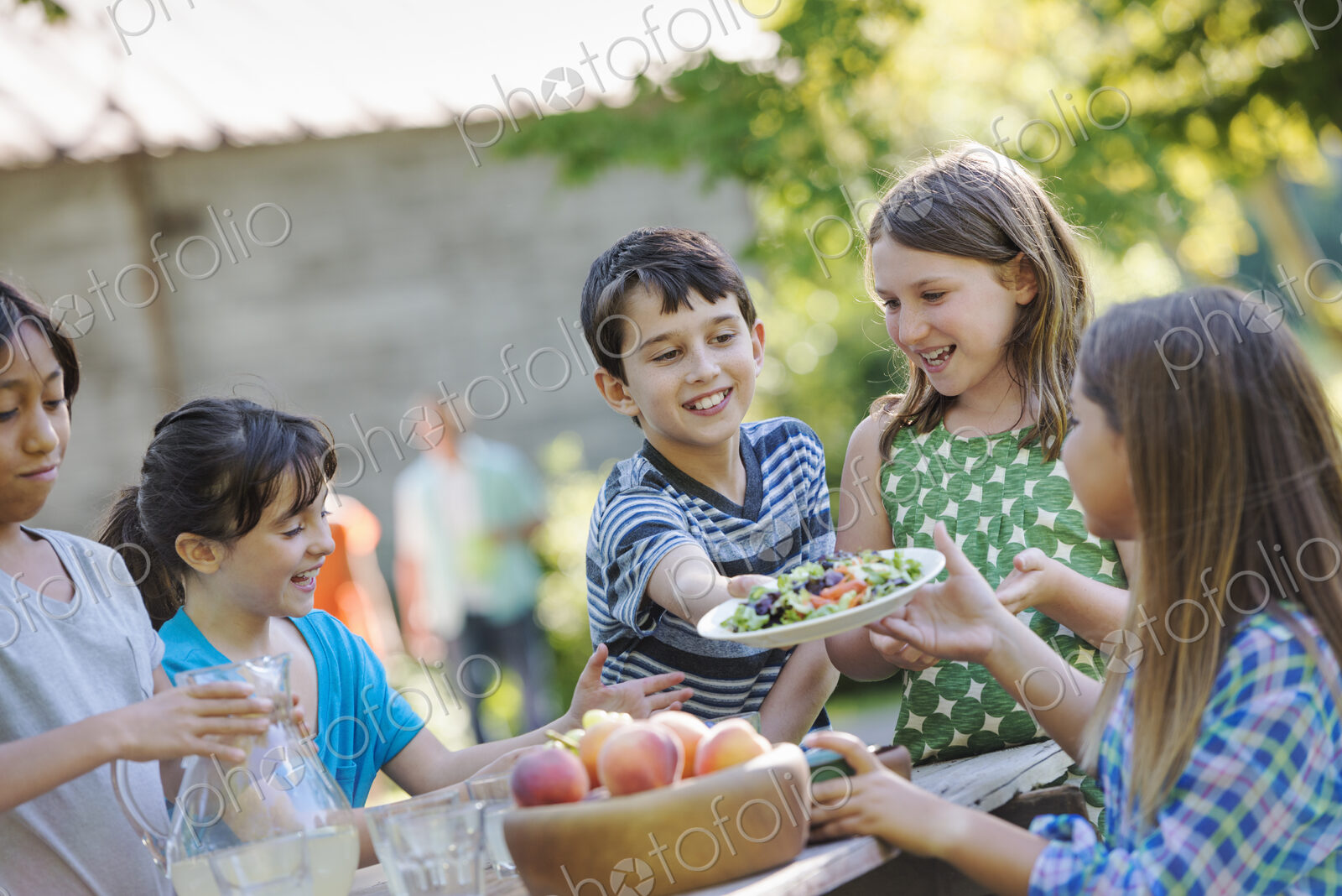 A group of children around a table, eating fresh fruits and salads.