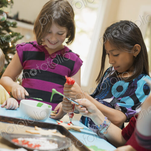 A group of children, girls and boys, around a table, decorating organic Christmas cookies. A group of children, girls and boys, around a table, decorating organic Christmas cookies.