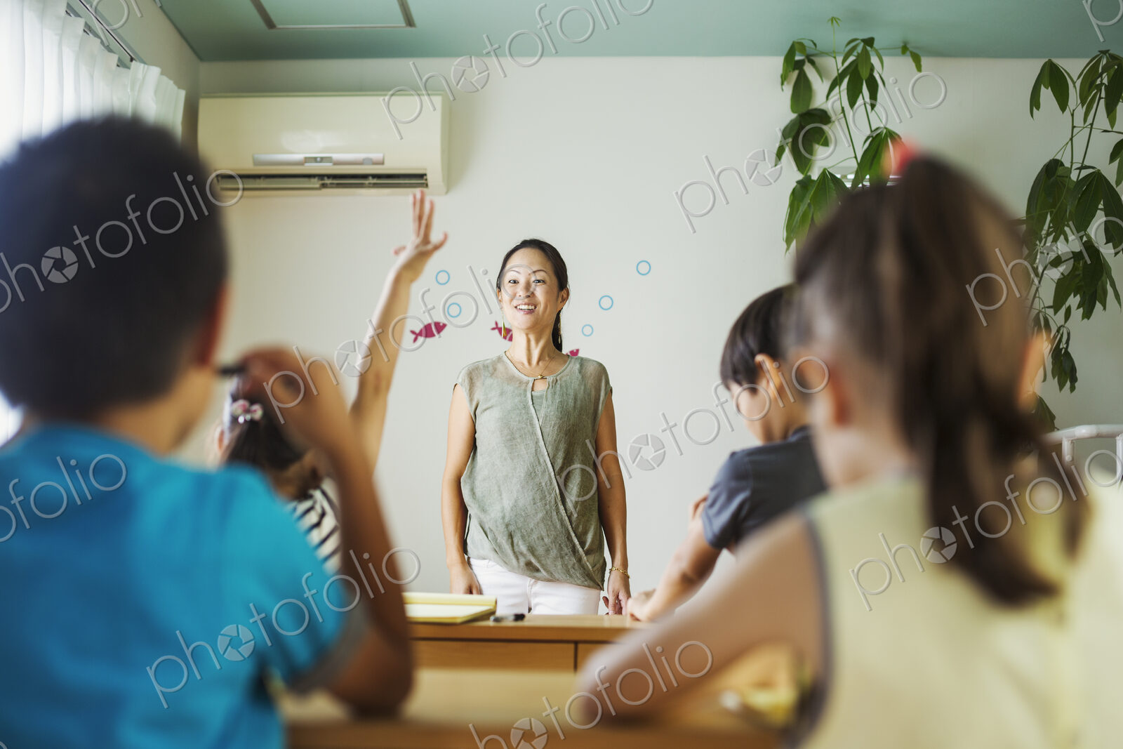 A group of children in a classroom, one with her hand up ready to answer a question.