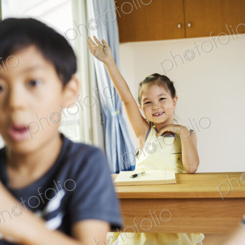 A group of children in a classroom, one with her hand up ready to answer a question. A group of children in a classroom, one with her hand up ready to answer a question.