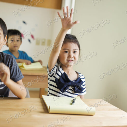 A group of children in a classroom, one with her hand up ready to answer a question. A group of children in a classroom, one with her hand up ready to answer a question.