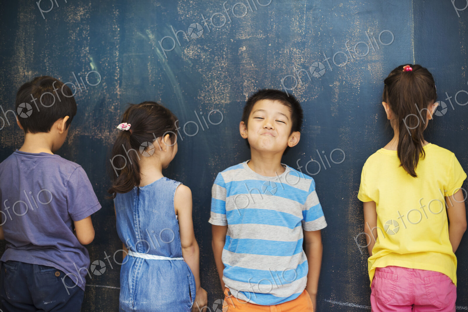 A group of children in school. Four children standing by the blackboard.