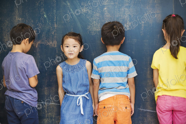 A group of children in school. Four children standing by the blackboard.