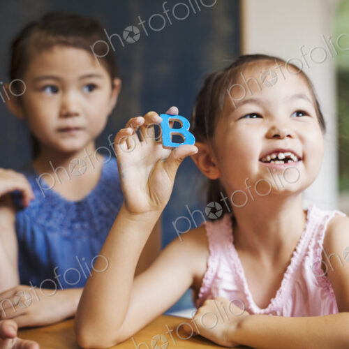 A group of children in school. Two boys and two girls holding up alphabet letters. A group of children in school. Two boys and two girls holding up alphabet letters.