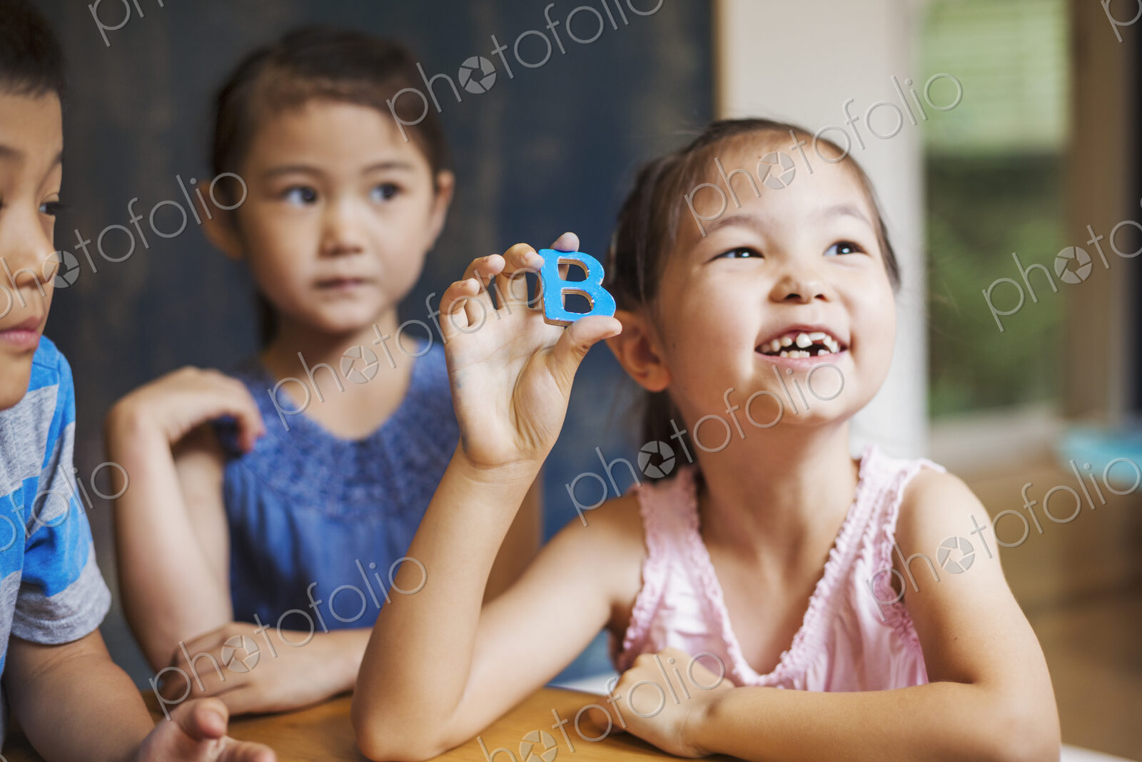 A group of children in school. Two boys and two girls holding up alphabet letters.